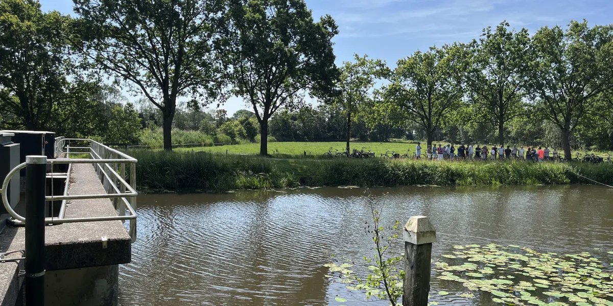 Deelnemers aan de fietstocht op 20 juni staan bij de stuw Blauwe Kamer