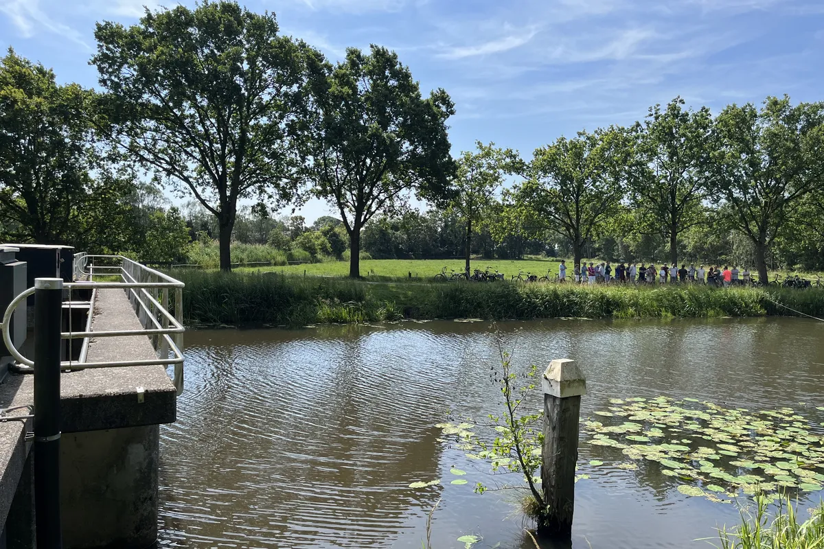 Deelnemers aan de fietstocht op 20 juni staan bij de stuw Blauwe Kamer