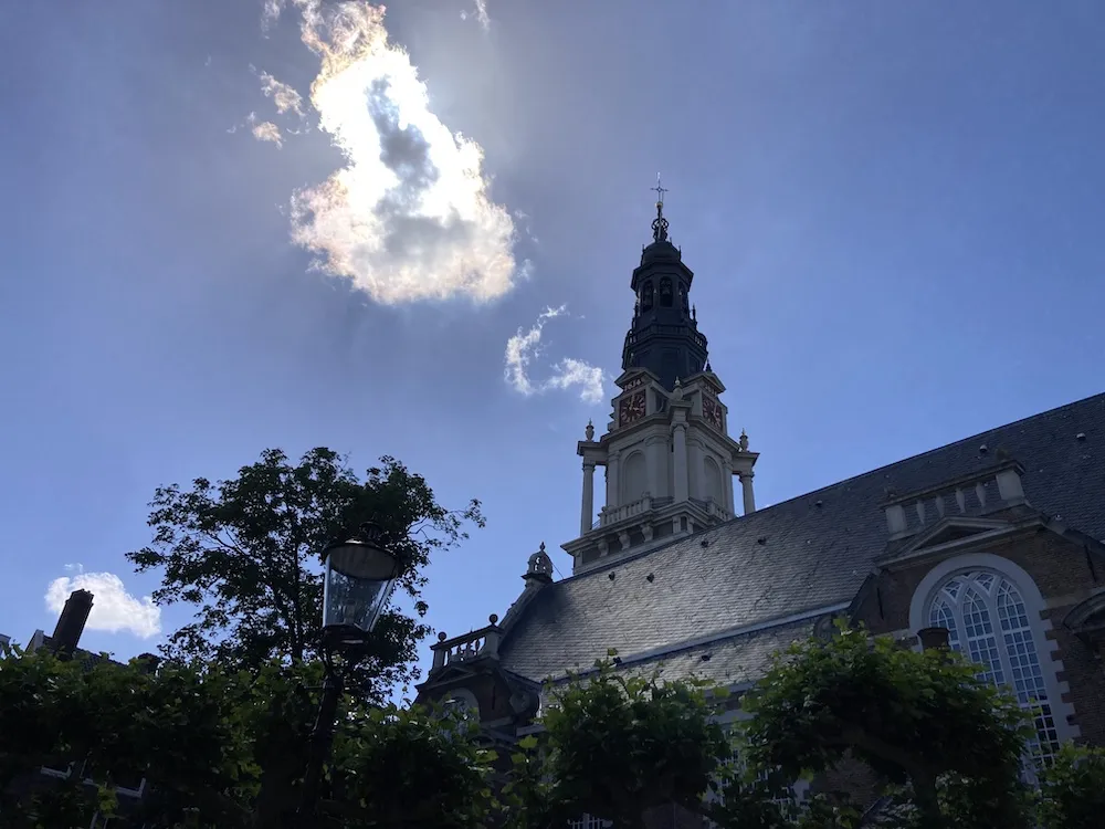 Exterior of the Zuiderkerk with bright blue sky and a few clouds.