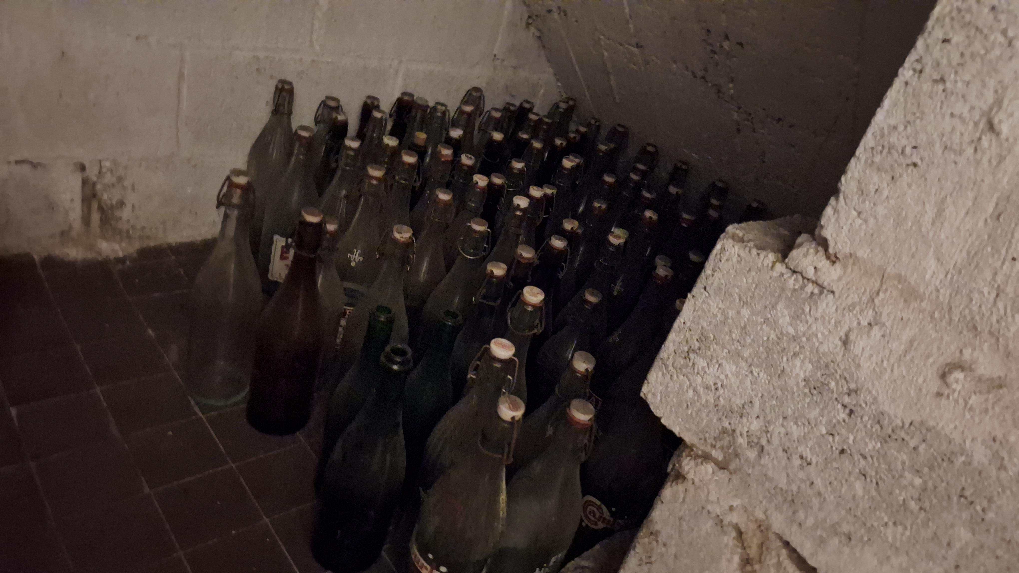 Grote partij lege glazen flessen verdeeld over de vloer en een houten krat – foto 2 – kavel bij Goeiendeal, Houthalen-Helchteren