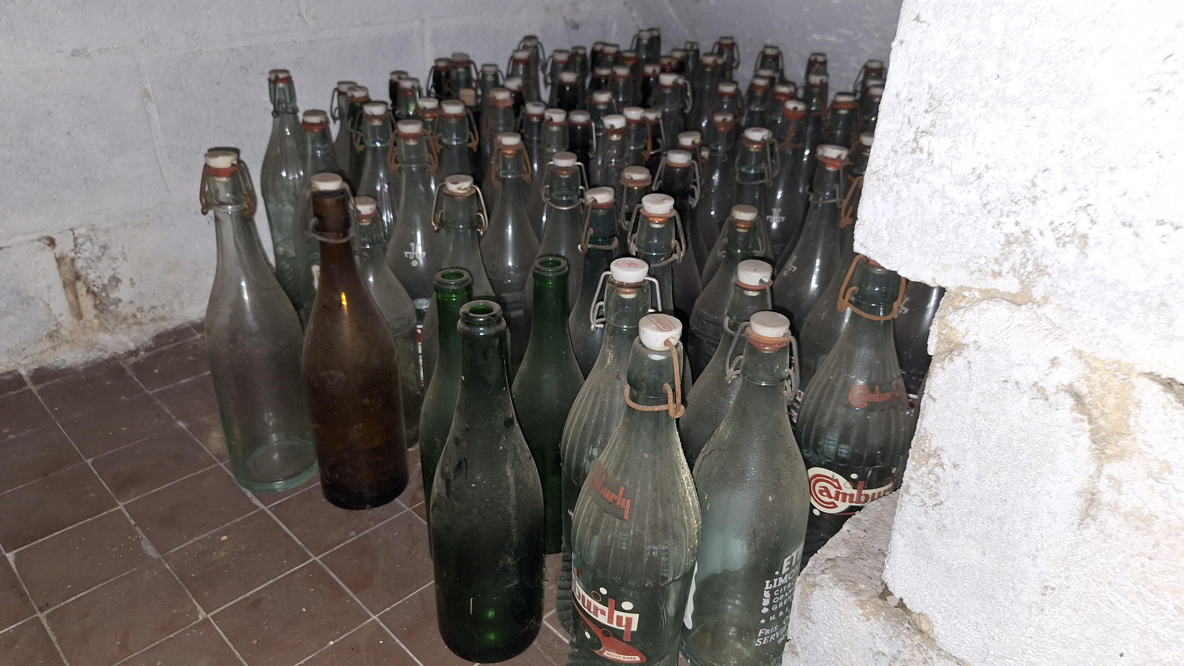 Grote partij lege glazen flessen verdeeld over de vloer en een houten krat – foto 5 – kavel bij Goeiendeal, Houthalen-Helchteren