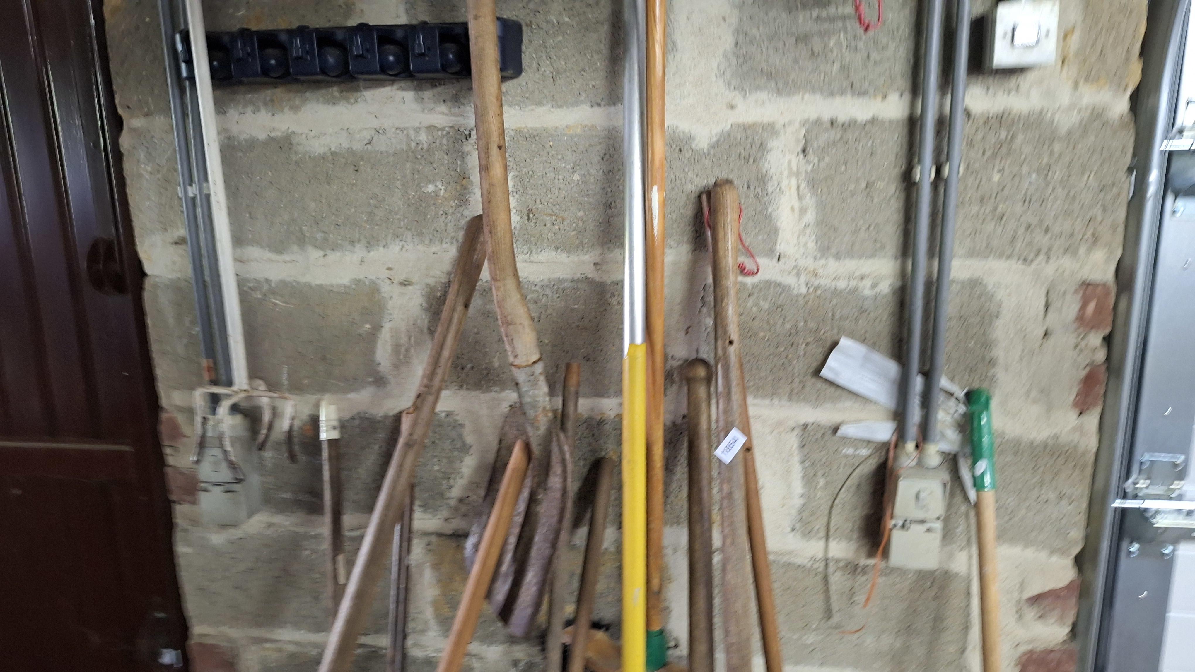 Partij divers tuingereedschap waaronder schoppen, bezems en een riek staand tegen een muur – foto 3 – kavel bij Goeiendeal, Houthalen-Helchteren