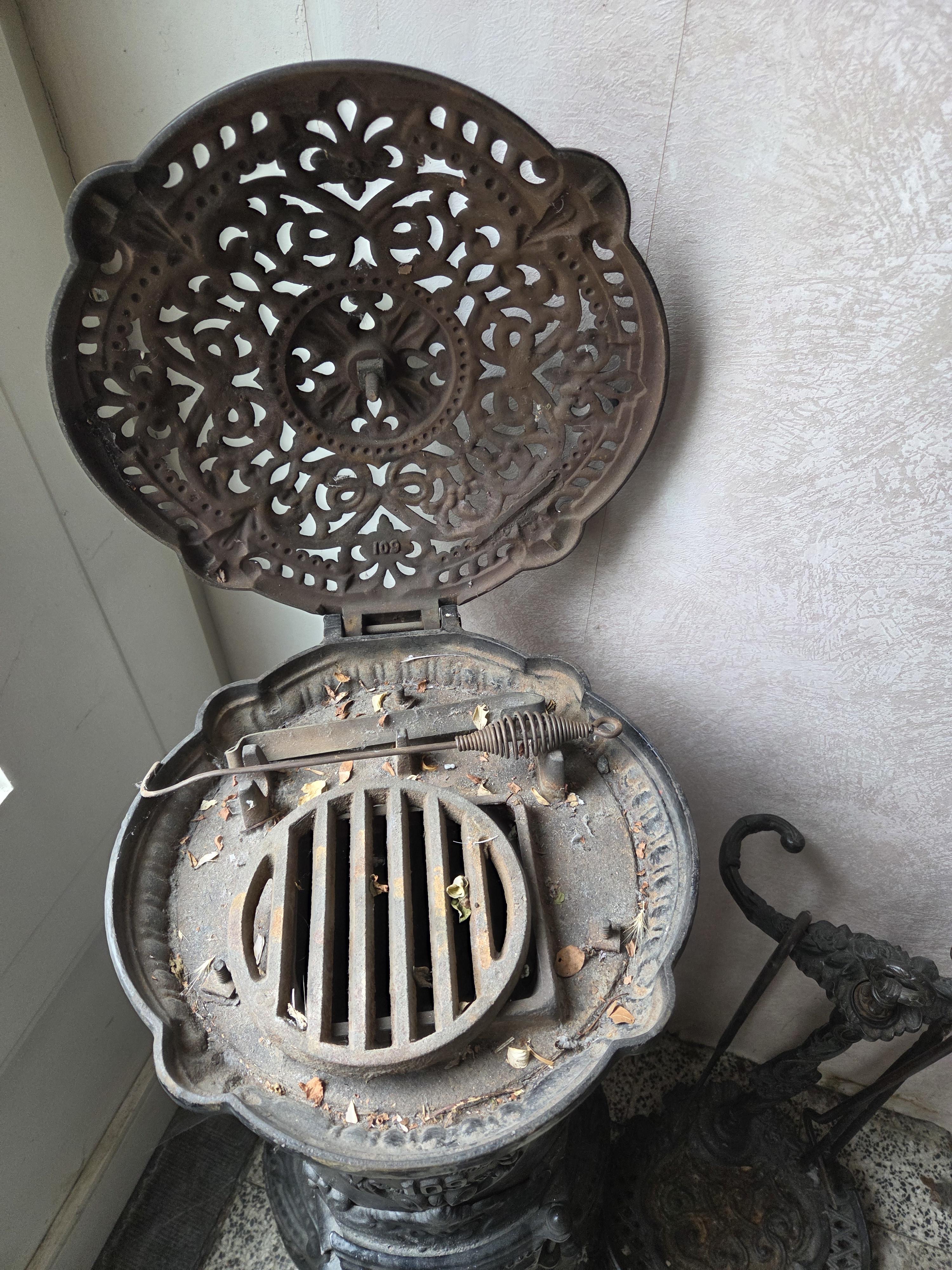 Klassieke ronde kolomkachel gietijzer(model nr. 109 "Ciney" Regence) met opengewerkte details en reliëfdecoratie, inclusief bijbehorend haardstel m… – foto 4 – kavel bij Goeiendeal