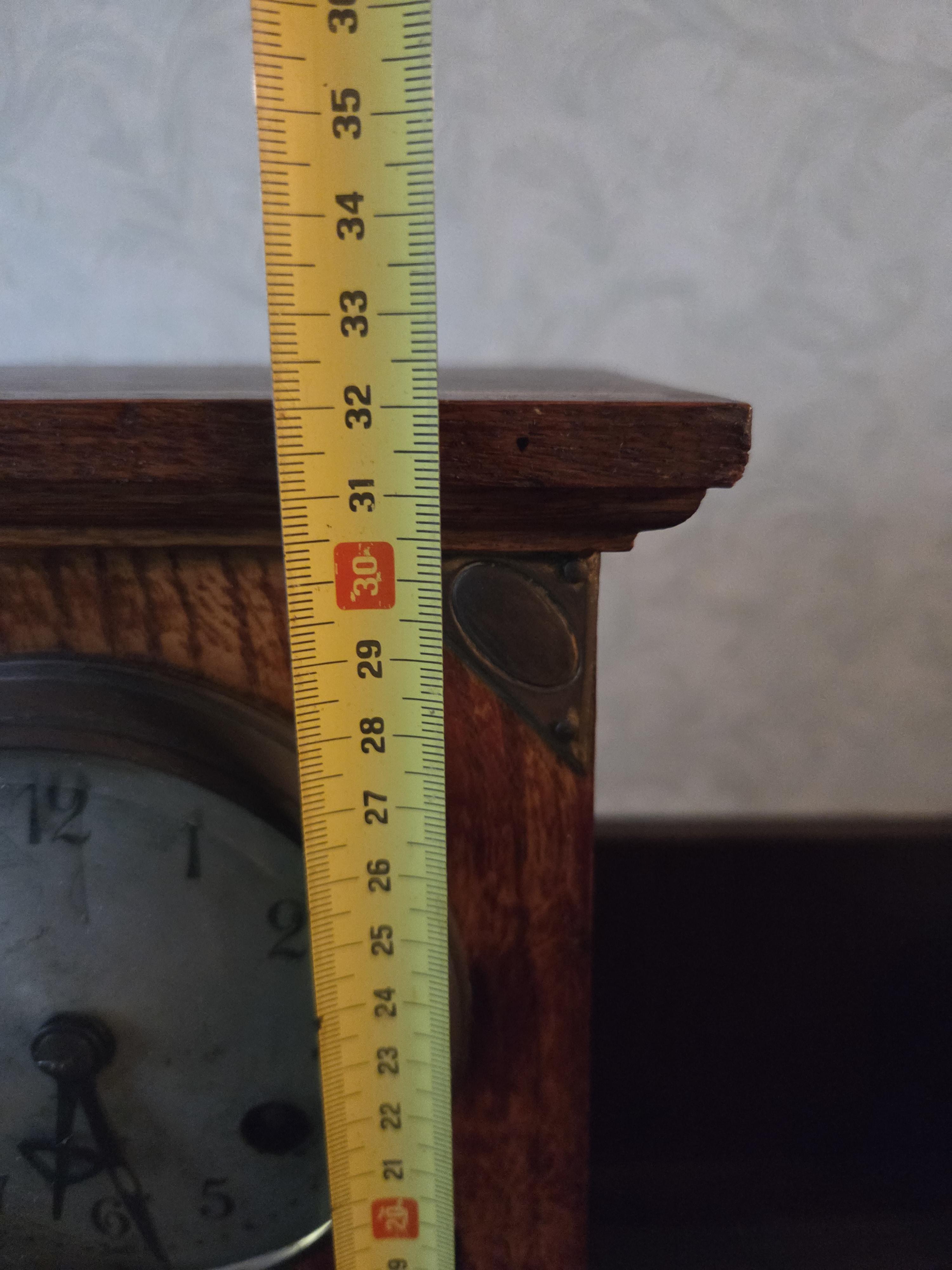 Klassieke schouwklok met een rechthoekige houten kast, ronde wijzerplaat en glas-in-lood venster onderaan – Lot 101 – foto 2 – kavel bij Goeiendeal, Jette