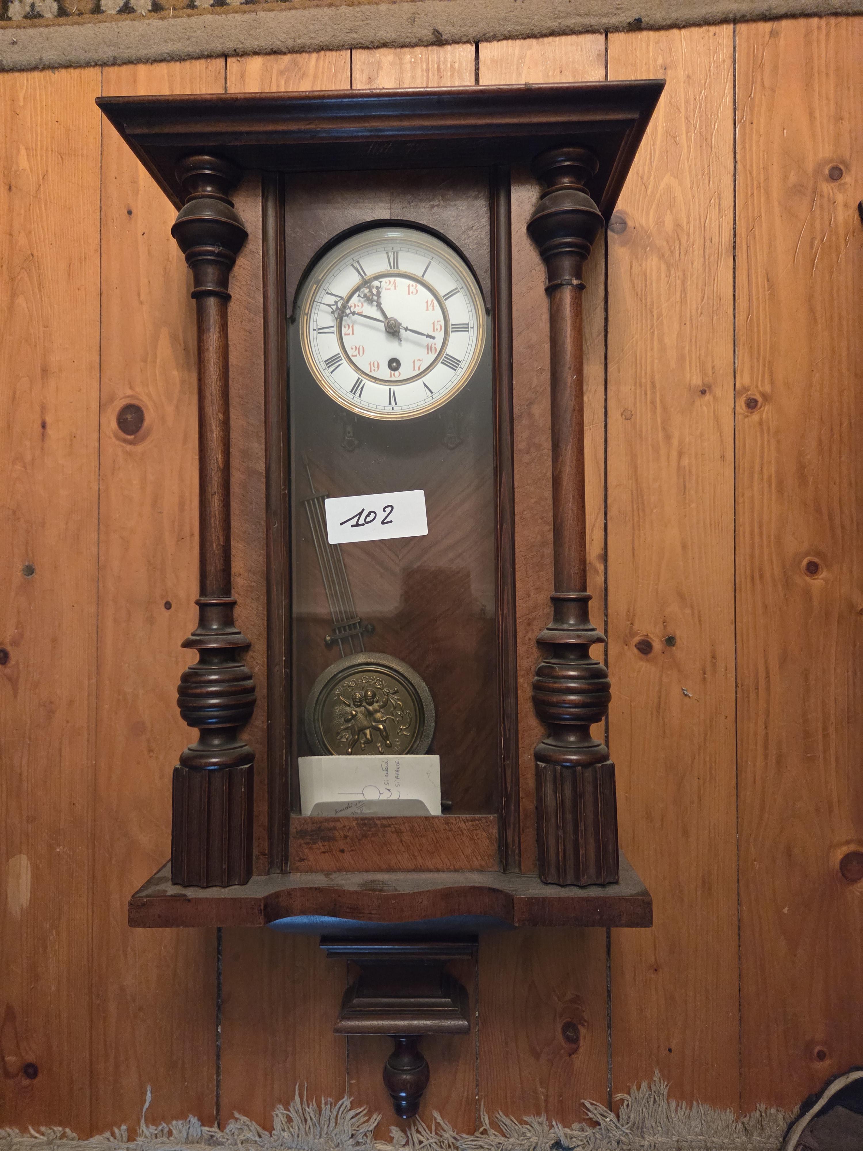 Regulateur wandklok met een gedecoreerde houten kast en een slinger voorzien van een reliëf – Lot 102 – kavel bij Goeiendeal, Jette