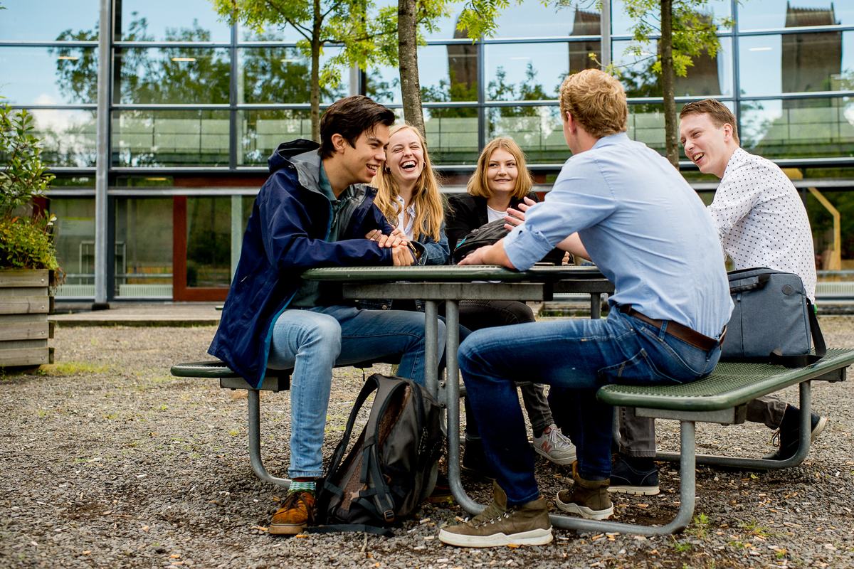 Groepje studenten aan een statafel voor HVHL gebouw Leeuwarden