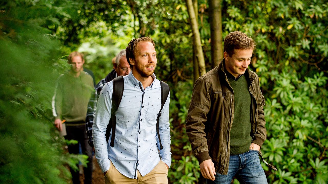Deeltijd studenten lopen door de tuin en bekijken landschapsinrichting