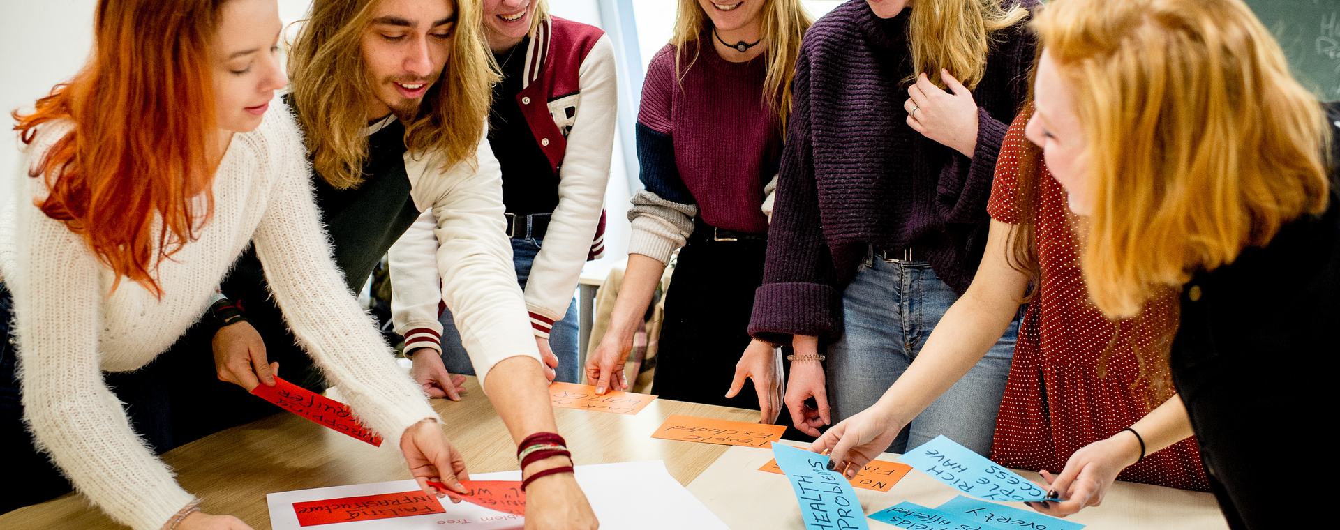Studenten HVHL staan om tafel en brainstormen met papier en post-its