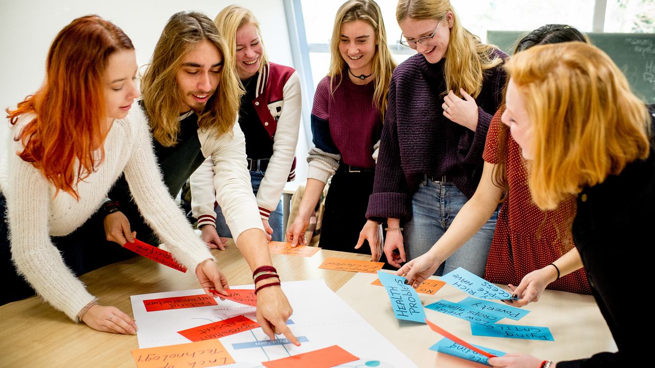 Studenten HVHL staan om tafel en brainstormen met papier en post-its
