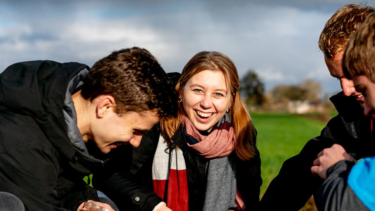 Studenten bestuderen een bodemmonster in een weiland