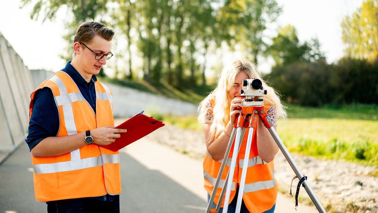 Twee studenten Land- en Watermanagement bezig met landmetingen