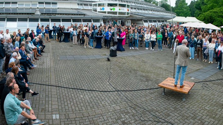 Docent houdt toespraak op het plein voor de school tijdens reunie Tuin en Landschapsinrichting