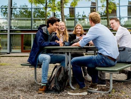 Groepje studenten aan een statafel voor HVHL gebouw Leeuwarden