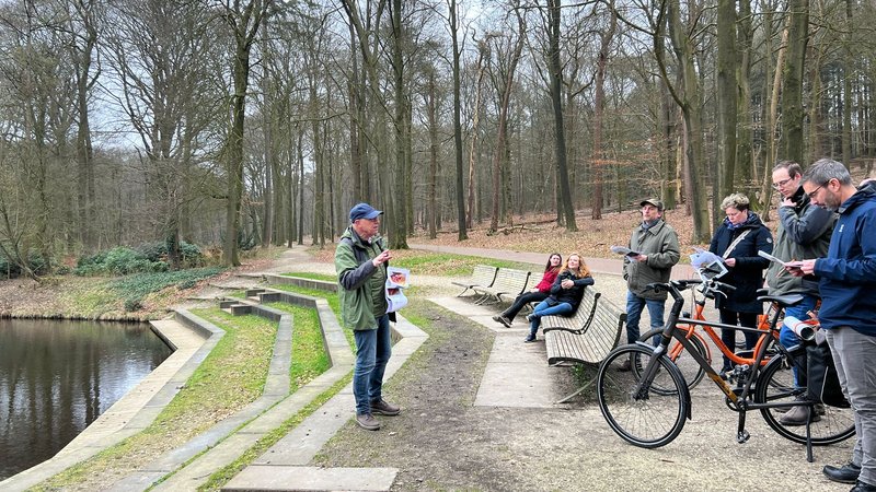 De docent geeft uitleg tijdens de fietsexcursie in het bos