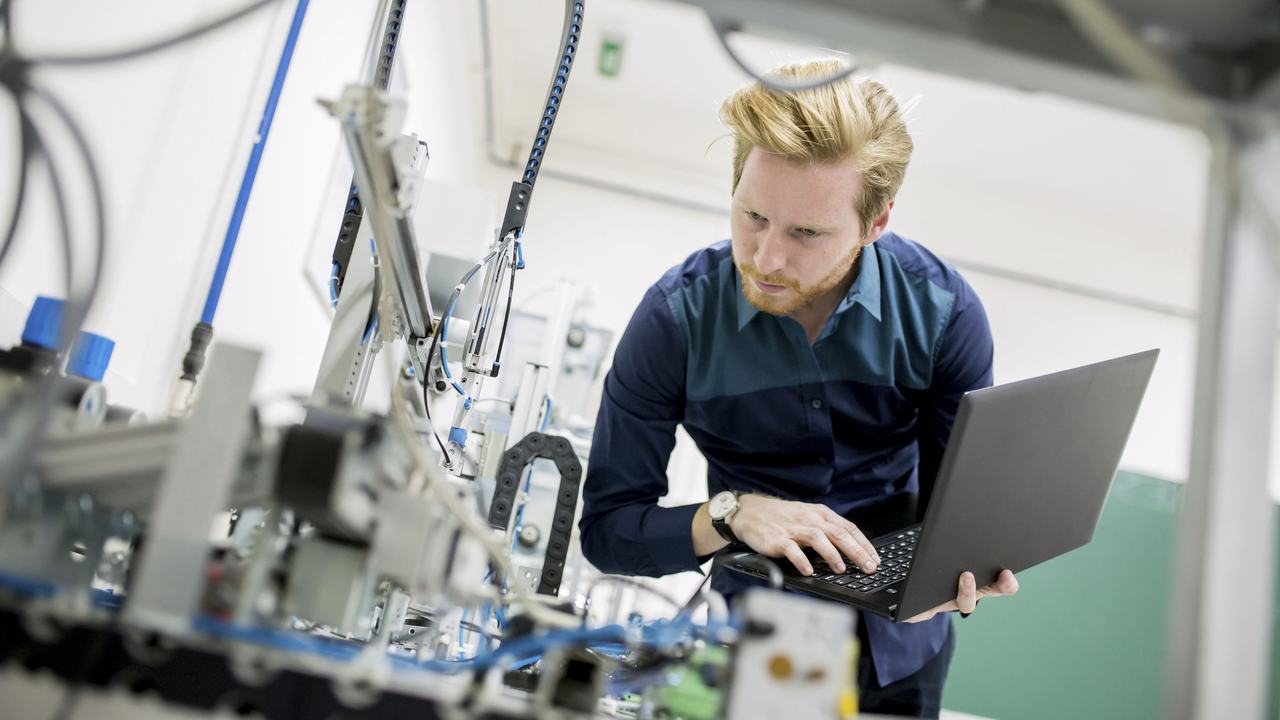 Student met laptop optimaliseert het proces in een fabriek