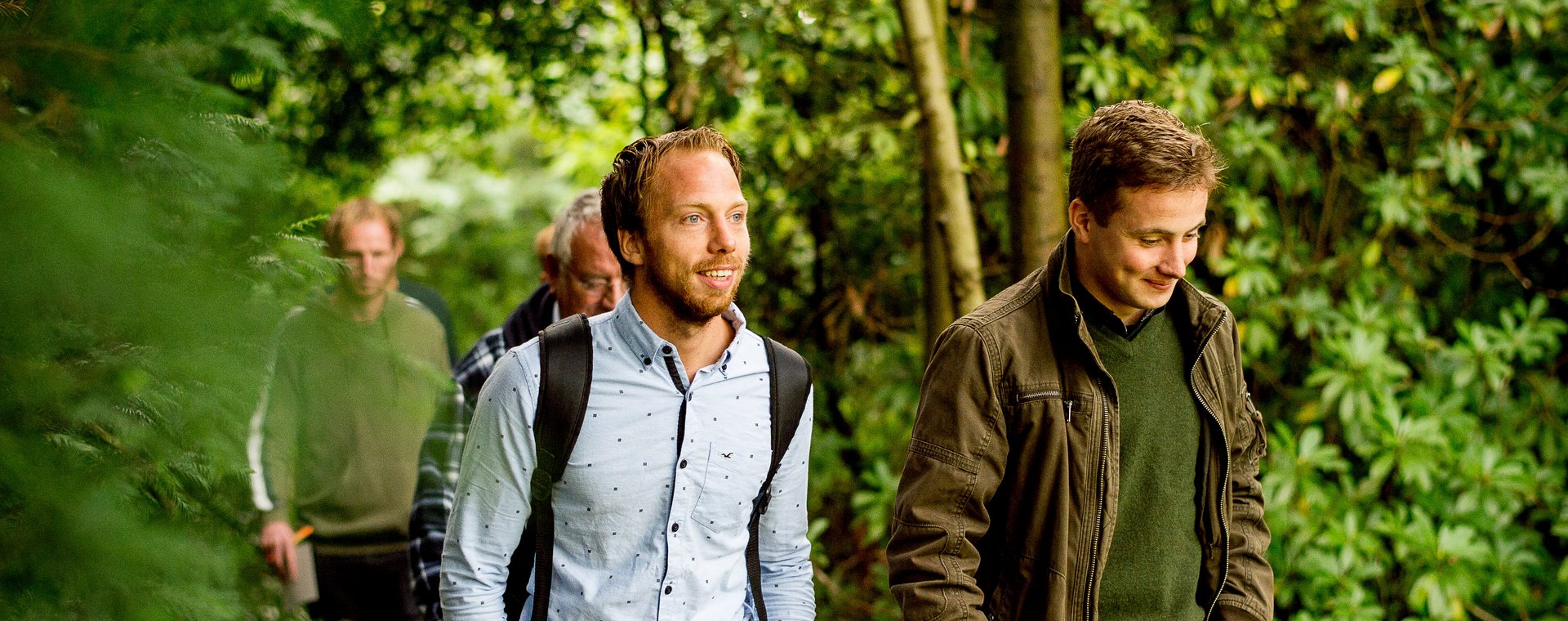 Deeltijd studenten lopen door de tuin en bekijken landschapsinrichting
