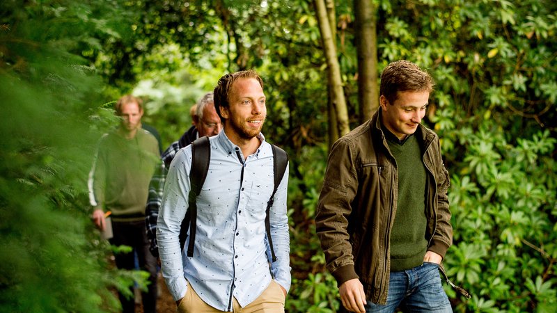 Deeltijd studenten lopen door de tuin en bekijken landschapsinrichting