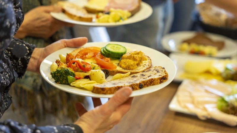 Iemand loopt langs een buffet met gezonden voeding