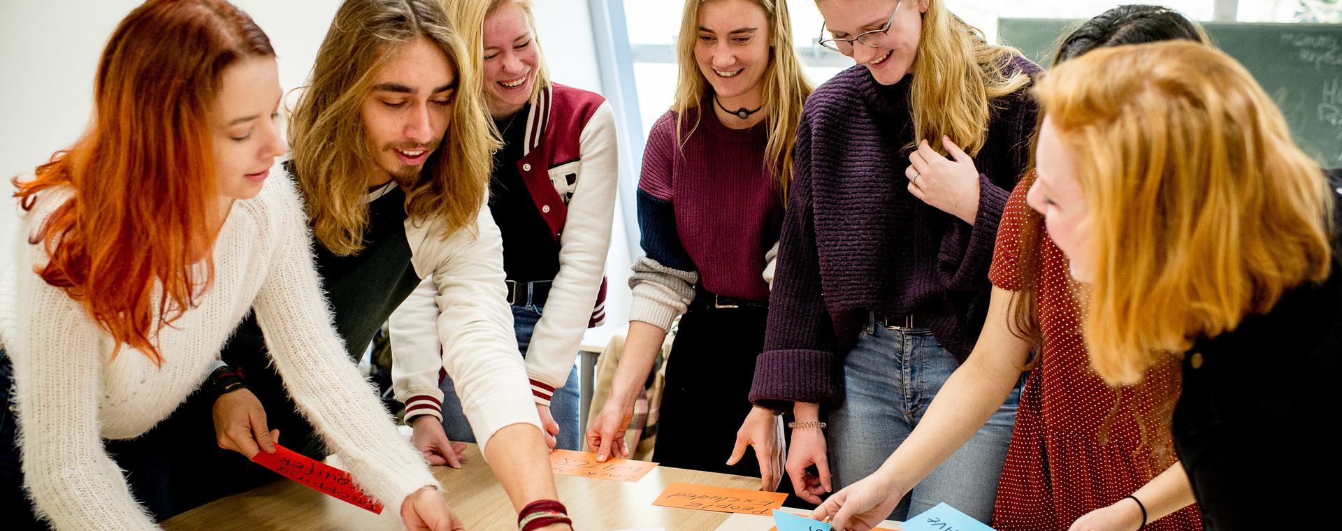 Studenten HVHL staan om tafel en brainstormen met papier en post-its