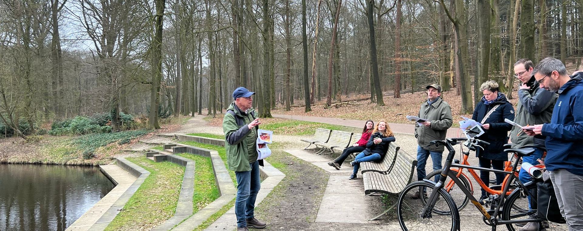 De docent geeft uitleg tijdens de fietsexcursie in het bos