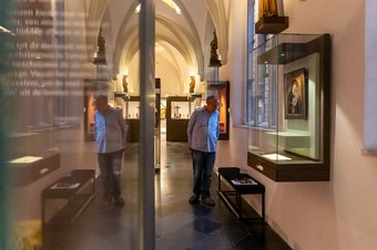 Bezoeker bekijkt kunstwerk in kloostergang - Foto: Cindy Bakker