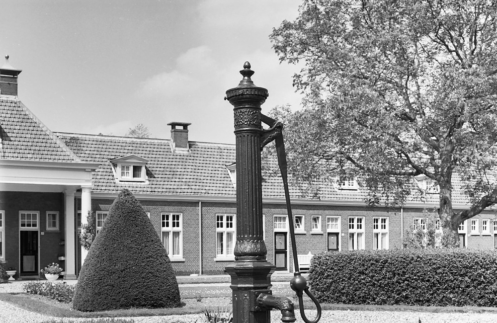Centraal in de binnenhof van het woningcomplex gelegen gietijzeren waterpomp
