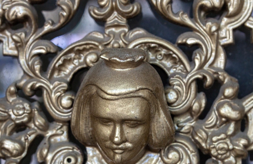 Detail deurrooster met afgebeelde mensenhoofden - 2016