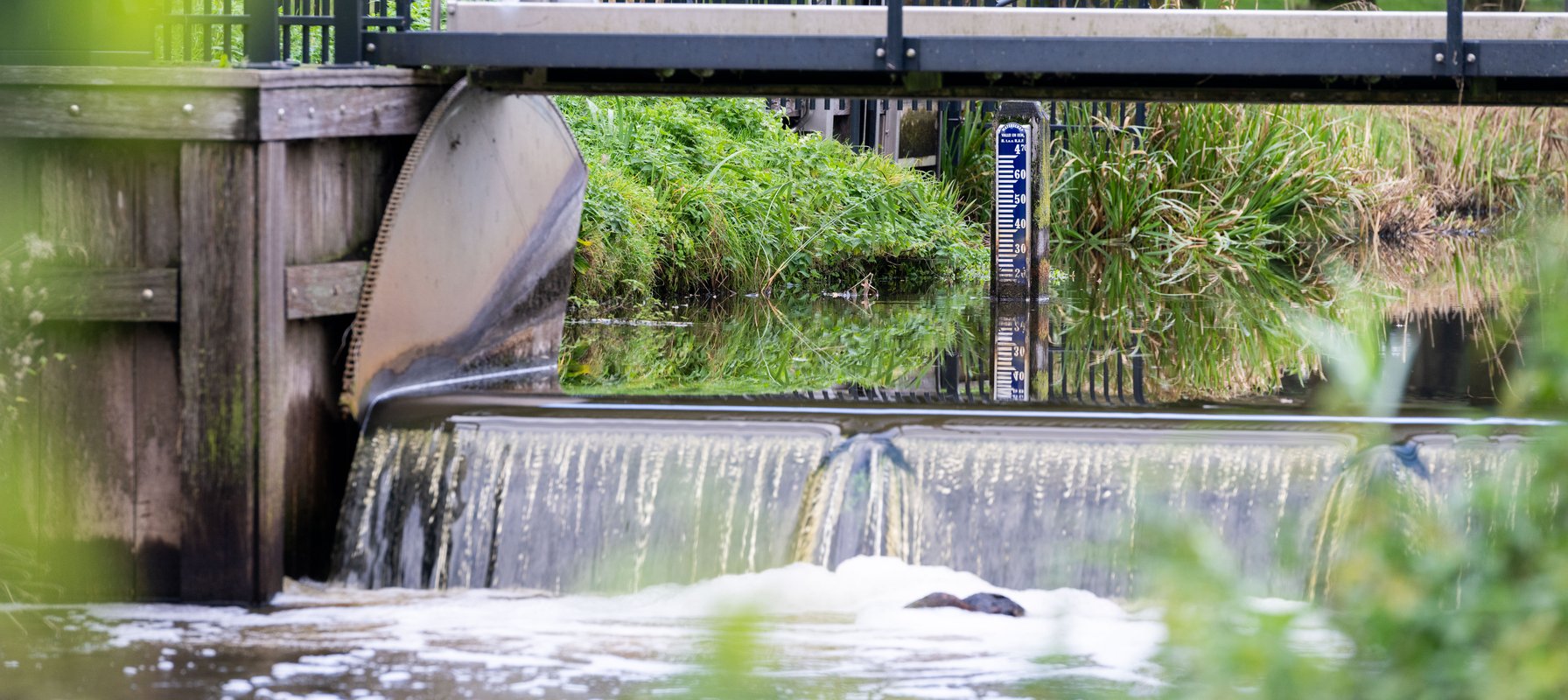 Foto van stuw Esvelderbeek met peilschaal op de achtergrond.